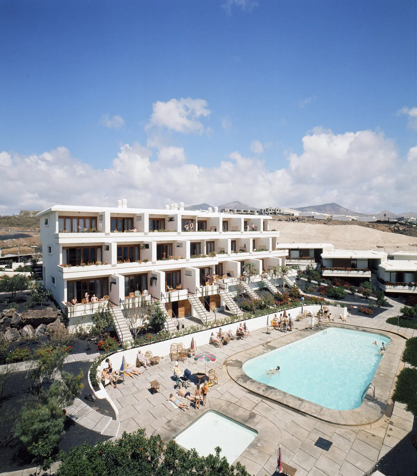 White terraced development with a pool and mountains behind