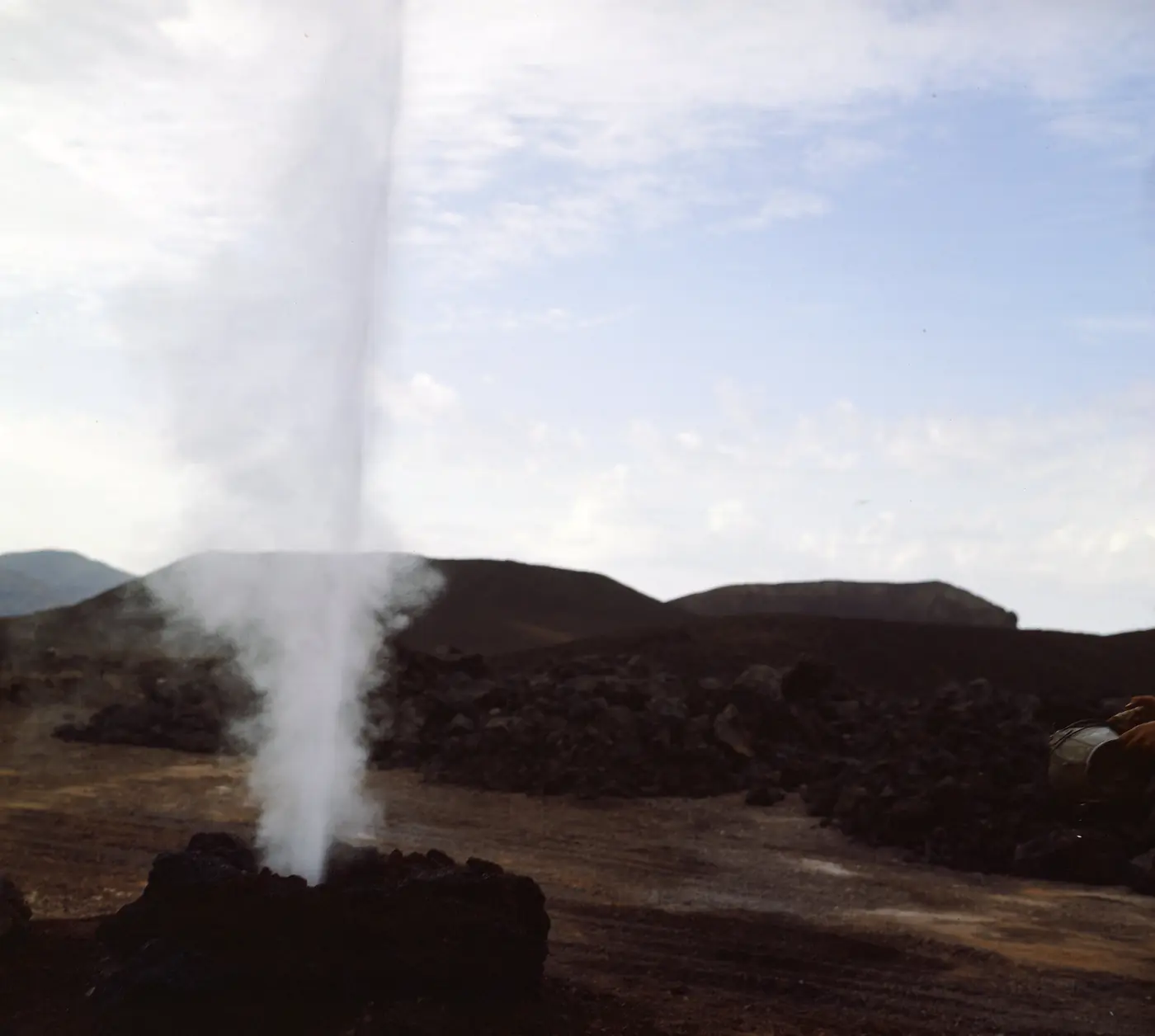 A column of steam rising from volcanic ground